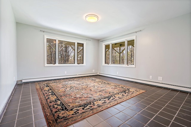 spare room with baseboards, a baseboard radiator, and dark tile patterned flooring