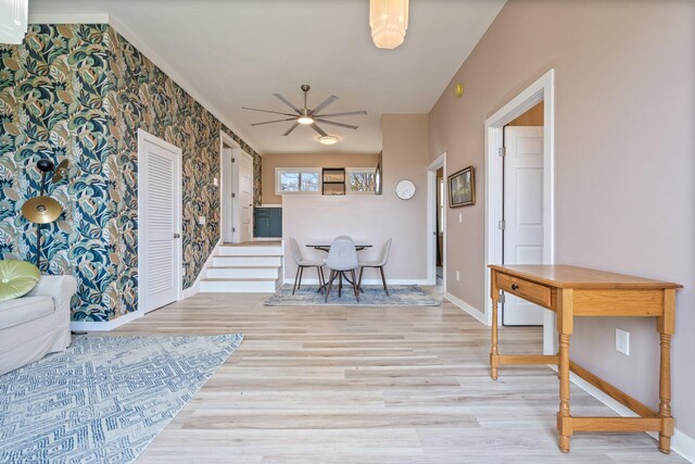 dining space with an accent wall, baseboards, ceiling fan, wallpapered walls, and light wood-style flooring