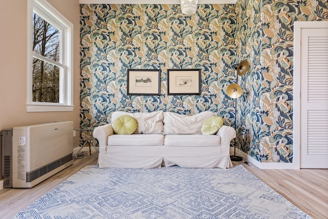 sitting room with heating unit, baseboards, wallpapered walls, and wood finished floors