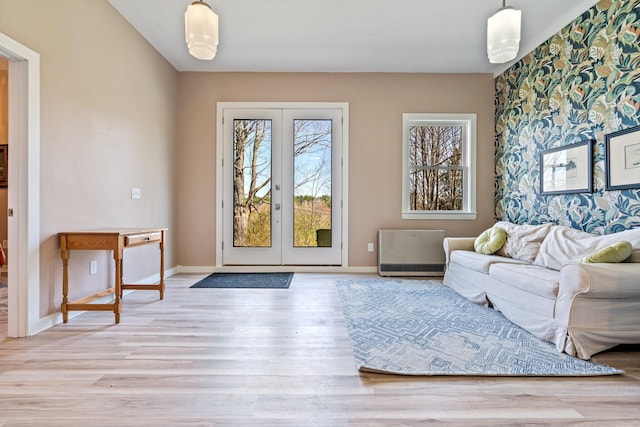 living area featuring light wood-type flooring, heating unit, baseboards, and french doors