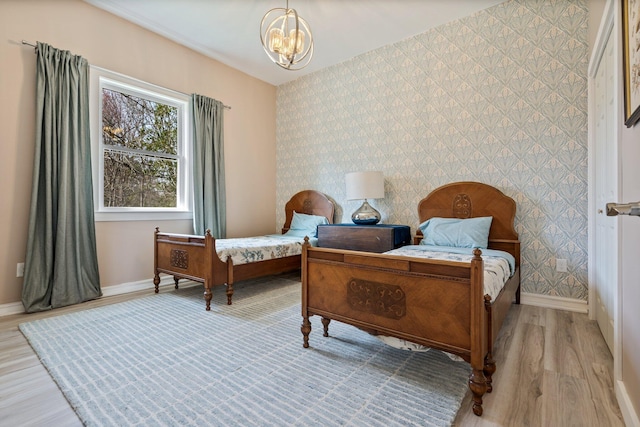 sitting room with an inviting chandelier, baseboards, light wood-style floors, an accent wall, and wallpapered walls