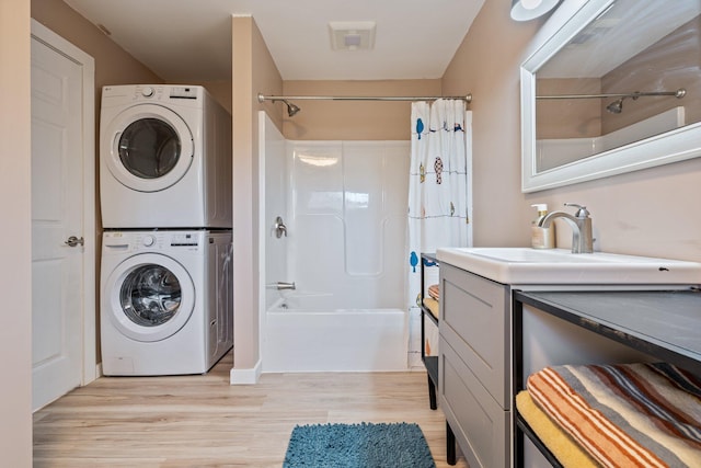 full bathroom featuring vanity, stacked washer / drying machine, wood finished floors, and shower / tub combo