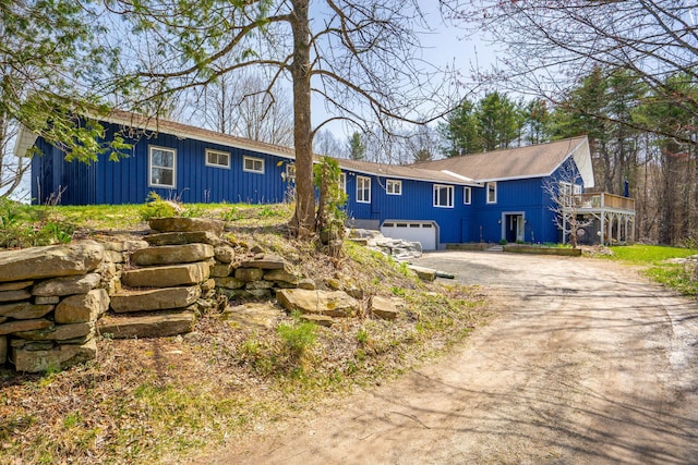 single story home with board and batten siding, an attached garage, and driveway