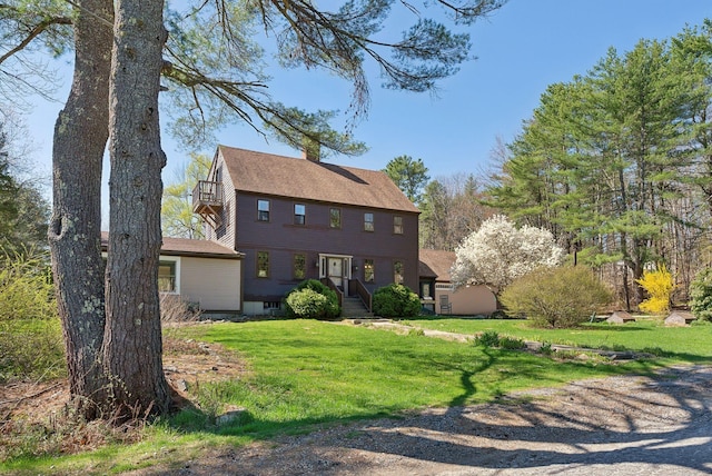 view of front of house featuring a chimney, roof with shingles, and a front lawn