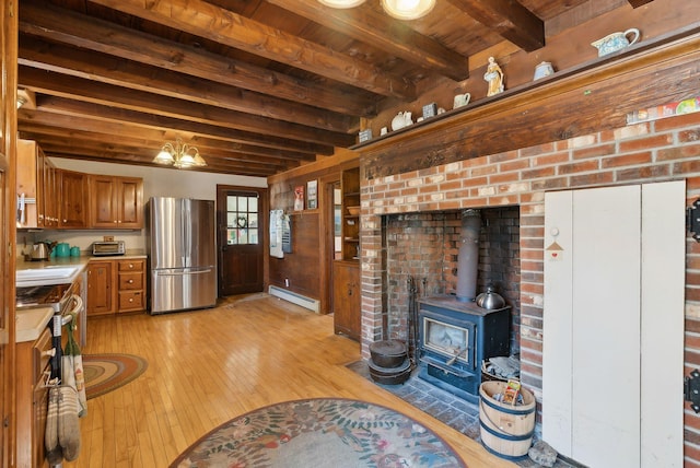 unfurnished living room featuring a wood stove, beam ceiling, wood ceiling, a baseboard radiator, and light wood-style flooring