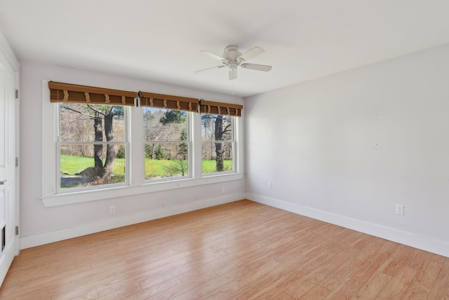empty room with baseboards, ceiling fan, and light wood finished floors
