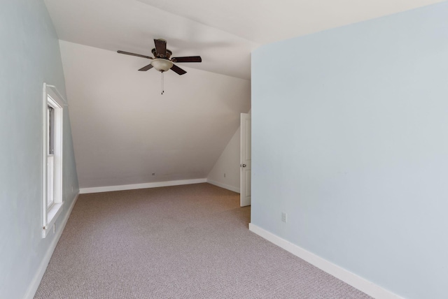 additional living space with light colored carpet, a ceiling fan, baseboards, and vaulted ceiling