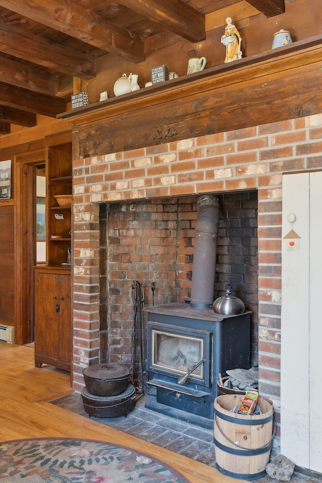 interior details with a wood stove, wood walls, wood finished floors, and a baseboard heating unit