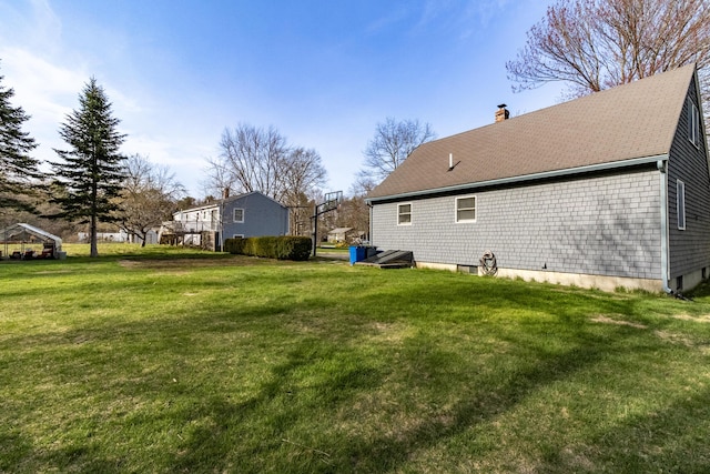 rear view of property with a lawn, a shingled roof, and a chimney