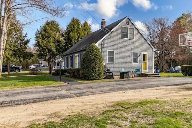 view of side of home with a lawn and a chimney