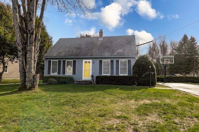 cape cod home featuring entry steps, a chimney, and a front lawn