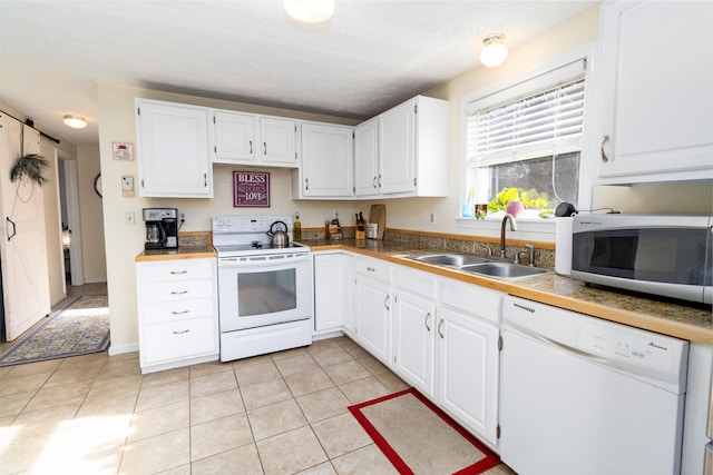 kitchen with white appliances, white cabinetry, a textured ceiling, a sink, and light tile patterned floors