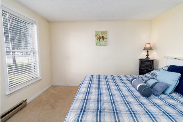 bedroom with baseboards, a baseboard radiator, carpet, and multiple windows