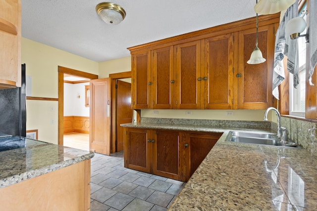 175 Summer St, Auburn, ME 04210 - kitchen with hanging light fixtures, brown cabinets, light stone counters, and a wainscoted wall