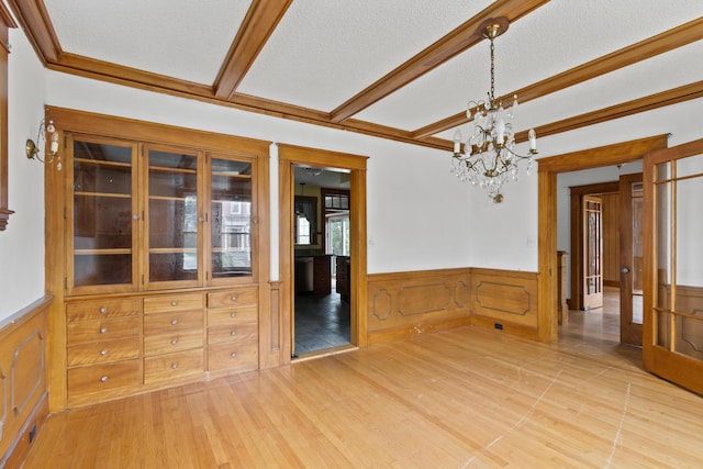 175 Summer St, Auburn, ME 04210 - unfurnished dining area featuring wainscoting, a chandelier, light wood-style floors, beam ceiling, and a textured ceiling