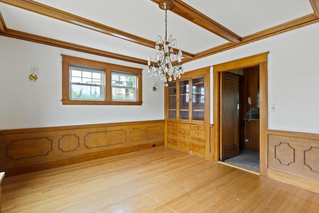 175 Summer St, Auburn, ME 04210 - unfurnished dining area with a chandelier, light wood-style floors, wainscoting, a textured ceiling, and crown molding