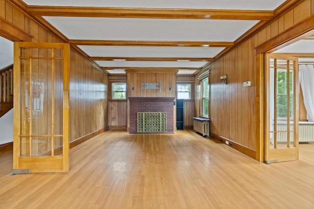 175 Summer St, Auburn, ME 04210 - unfurnished living room featuring radiator, beamed ceiling, wood finished floors, a fireplace, and wood walls