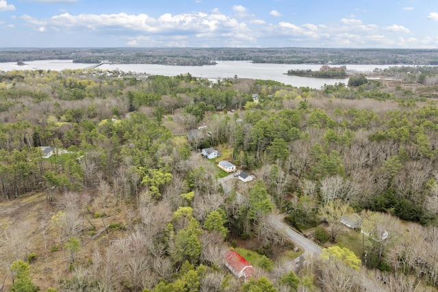 aerial view of property and surrounding area with a nearby body of water and a forest