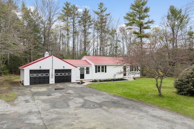 view of front facade featuring an attached garage, driveway, a front yard, and metal roof