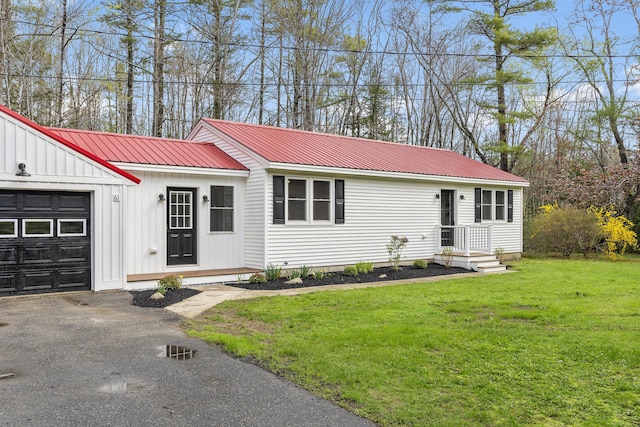 view of front of property with metal roof, a front yard, asphalt driveway, board and batten siding, and an attached garage