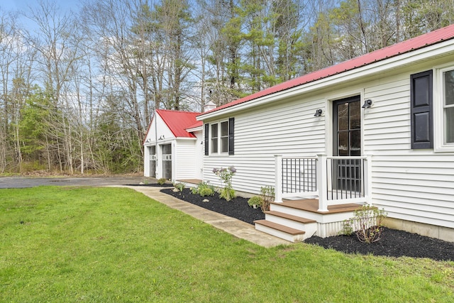 view of side of home with a lawn, metal roof, and a detached garage