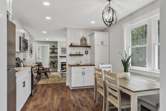 kitchen with stainless steel appliances, butcher block countertops, open shelves, dark wood-style floors, and a chandelier