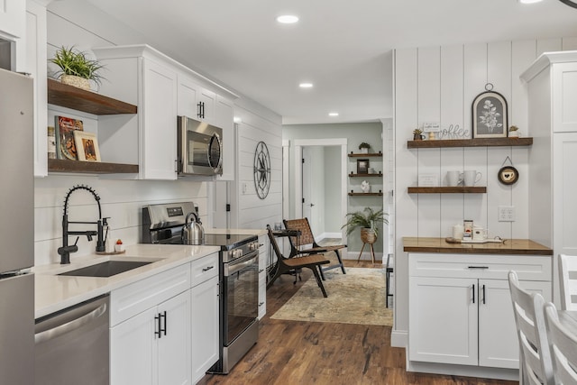 kitchen featuring open shelves, stainless steel appliances, a sink, recessed lighting, and dark wood-style flooring