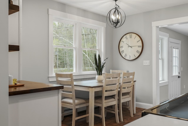 dining space featuring dark wood-type flooring, plenty of natural light, a chandelier, and baseboards