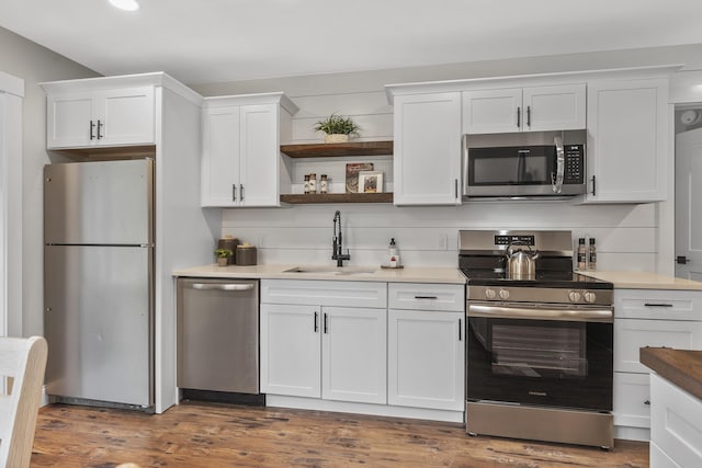kitchen with stainless steel appliances, a sink, white cabinetry, dark wood-style floors, and open shelves