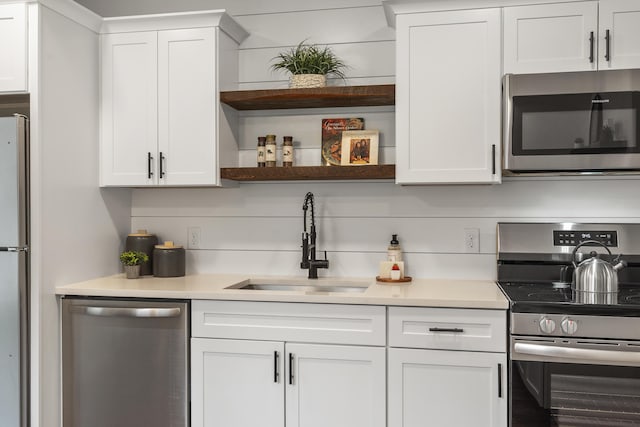 kitchen featuring stainless steel appliances, a sink, white cabinets, and light countertops