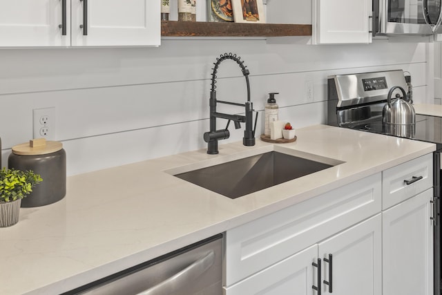 kitchen with appliances with stainless steel finishes, a sink, and white cabinetry