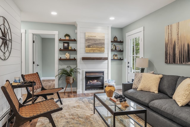 living area with wood finished floors, a baseboard radiator, a large fireplace, and recessed lighting
