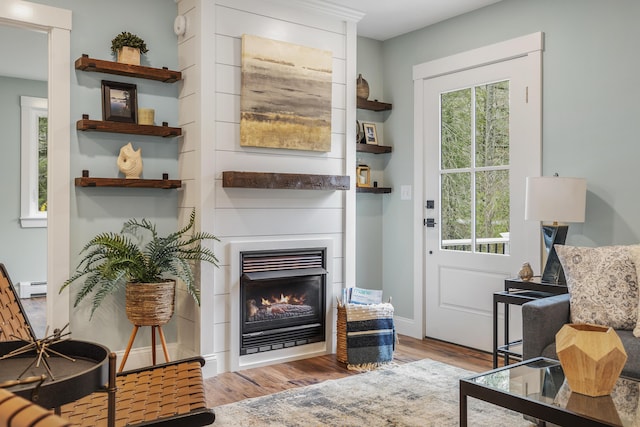 doorway featuring wood finished floors, a glass covered fireplace, and baseboard heating