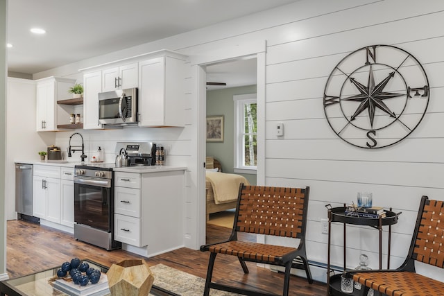 bar area featuring appliances with stainless steel finishes, wood finished floors, recessed lighting, a sink, and tasteful backsplash
