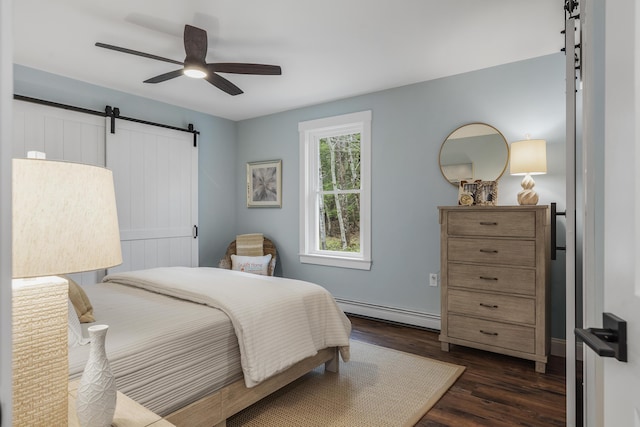 bedroom featuring a barn door, a baseboard heating unit, dark wood-type flooring, and a ceiling fan