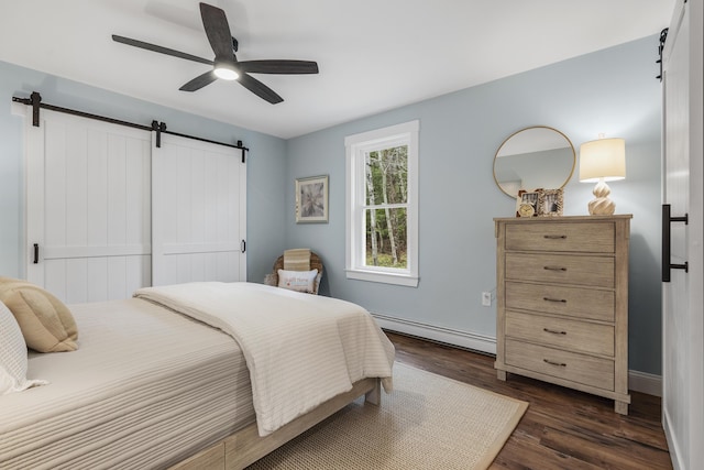 bedroom with baseboard heating, a barn door, dark wood finished floors, ceiling fan, and baseboards