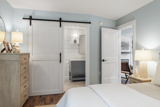 bedroom featuring a barn door, dark wood-type flooring, and ensuite bathroom