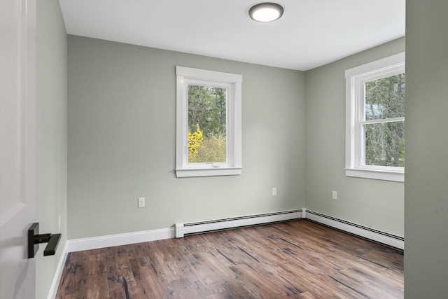 unfurnished room with plenty of natural light, wood finished floors, a baseboard heating unit, and baseboards