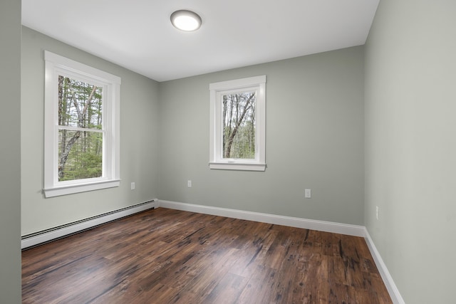 empty room featuring baseboard heating, dark wood-type flooring, and baseboards