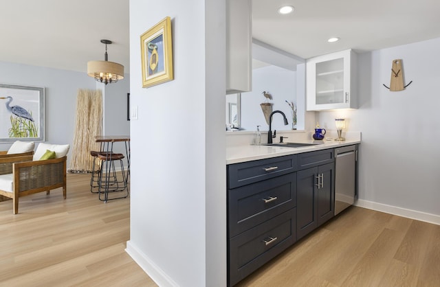bar with a sink, stainless steel dishwasher, light wood-style flooring, baseboards, and recessed lighting