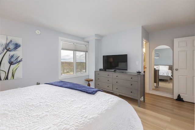 bedroom with light wood-style flooring and arched walkways