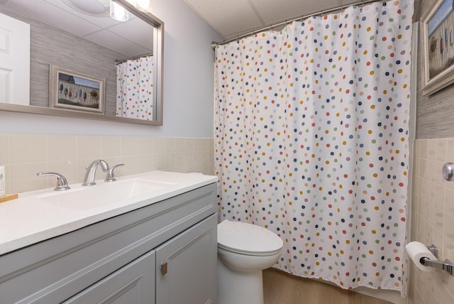 bathroom featuring tile walls, a paneled ceiling, toilet, vanity, and a shower with shower curtain