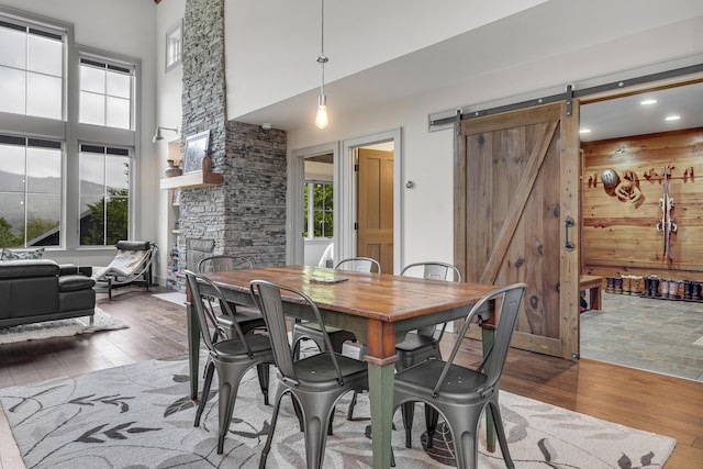 28 Fisher Rd, Newry, ME 04261 - dining area with a towering ceiling, hardwood / wood-style floors, a barn door, wood walls, and recessed lighting