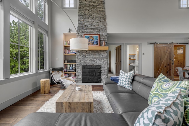 28 Fisher Rd, Newry, ME 04261 - living area with a barn door, wood finished floors, a high ceiling, and a fireplace