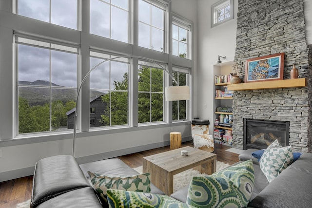 28 Fisher Rd, Newry, ME 04261 - living area featuring wood finished floors, baseboards, a fireplace, and a towering ceiling