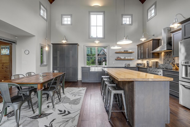 28 Fisher Rd, Newry, ME 04261 - kitchen with wood counters, a towering ceiling, wall chimney range hood, a center island, and appliances with stainless steel finishes