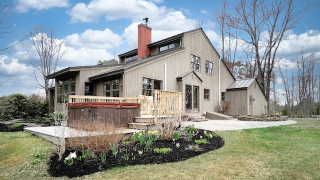 back of property featuring a lawn, a chimney, a deck, and metal roof