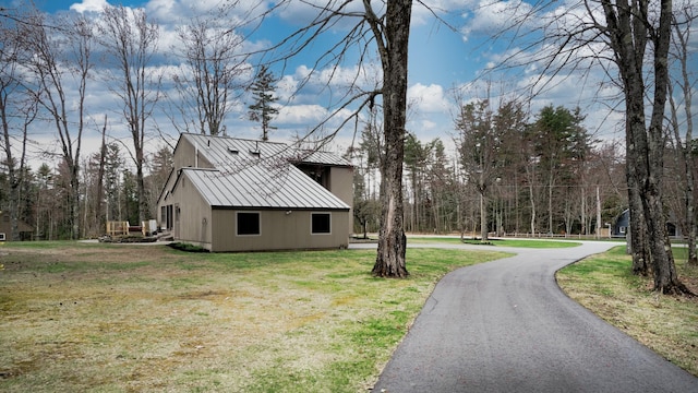view of property exterior featuring a lawn, a standing seam roof, and metal roof
