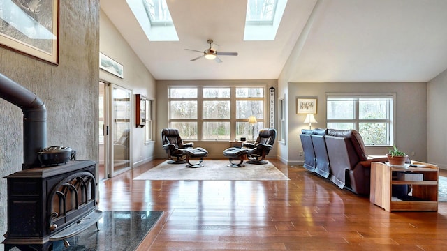 living area featuring a wood stove, wood finished floors, a wealth of natural light, and a skylight
