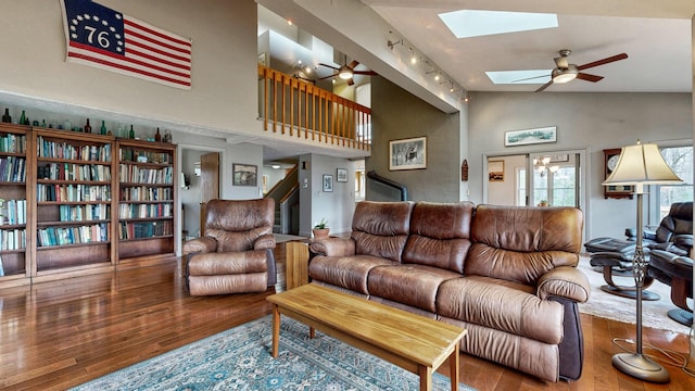 living room featuring track lighting, stairs, a ceiling fan, wood finished floors, and a skylight